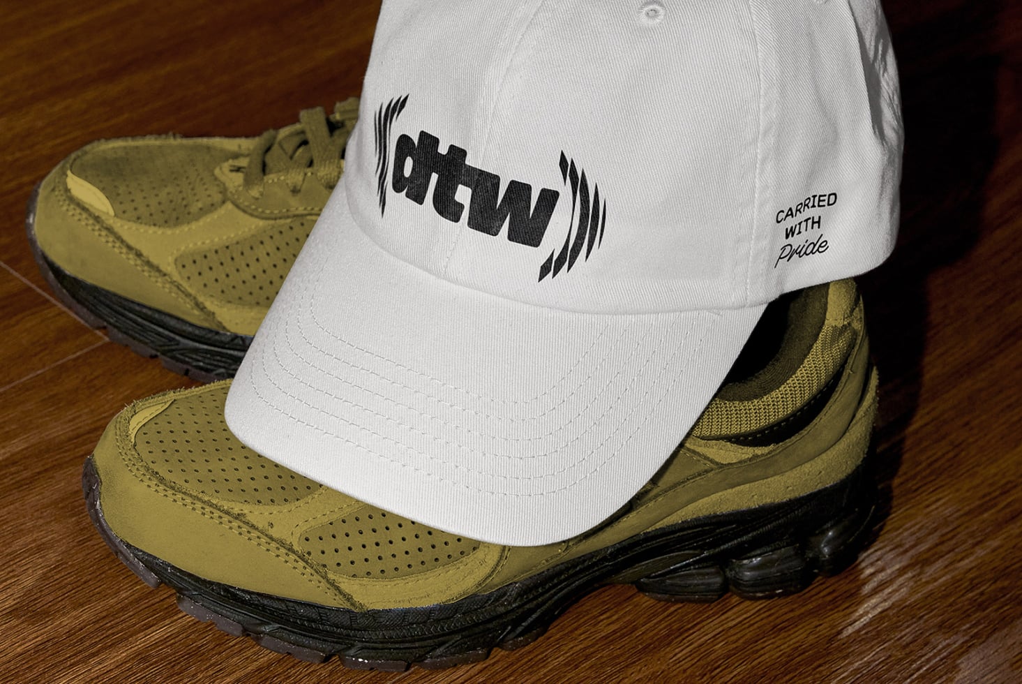 White cap ohtwn logo resting on tan hiking boot close up