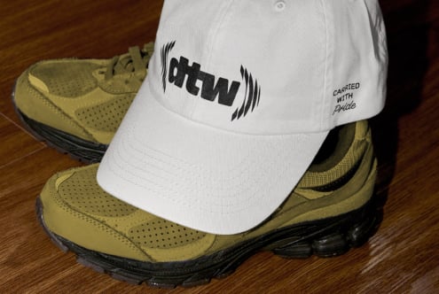 White cap ohtwn logo resting on tan hiking boot close up