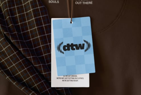 Blue hang tag mockup with checkered pattern on brown sweatshirt