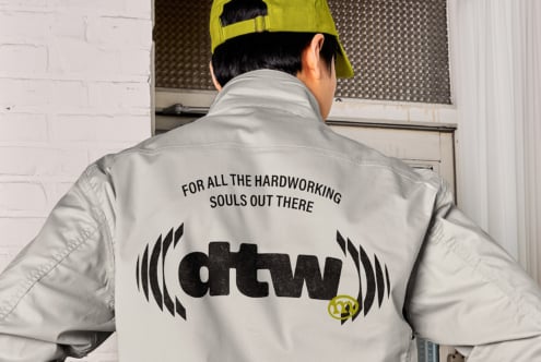 Cream windbreaker back view with workwear graphic, neon yellow cap visible