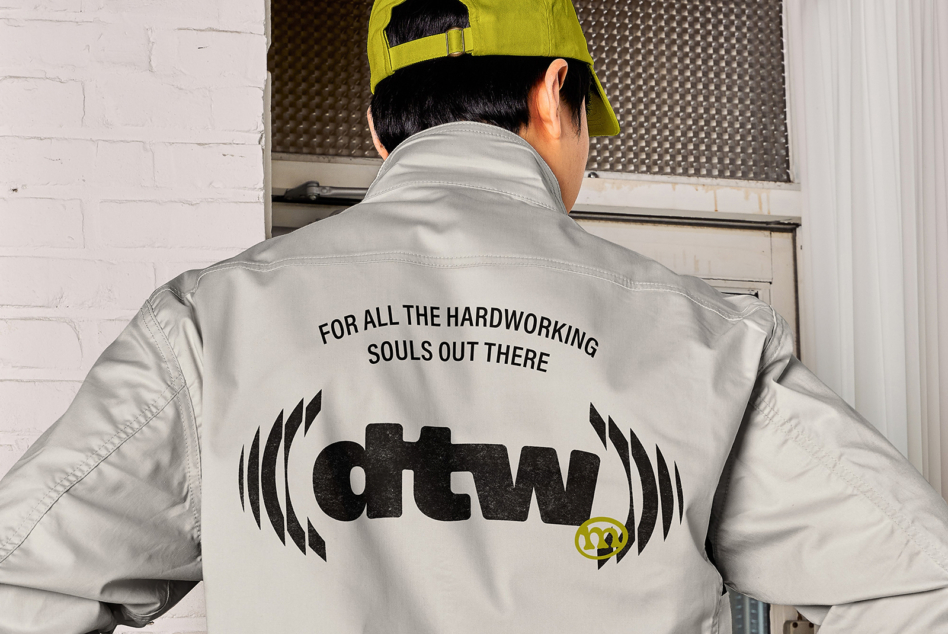 Cream windbreaker back view with workwear graphic, neon yellow cap visible