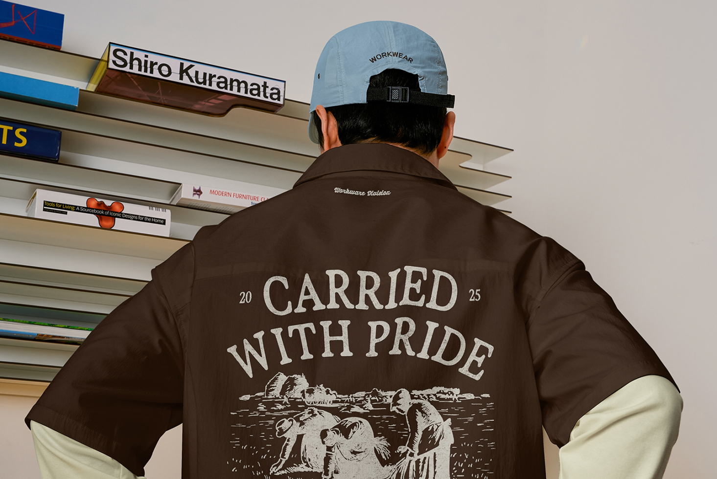 Brown shirt back showing carried with pride graphic, light blue workwear cap