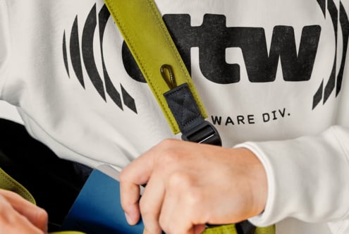 Lime green strap with black attachment point on white graphic sweatshirt close-up