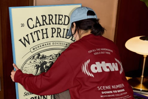 Maroon jacket held up showing cream workwear division poster