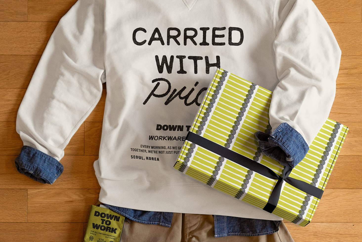 Person holding yellow patterned clutch wearing white sweatshirt with Carried with Pride design