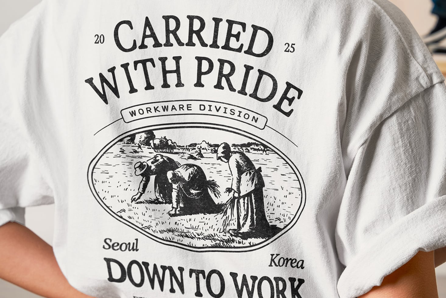 Person wearing white crewneck tee with retro workwear design from Seoul Korea