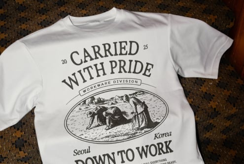 White tee with vintage workwear graphic saying Carried With Pride, worn flat lay