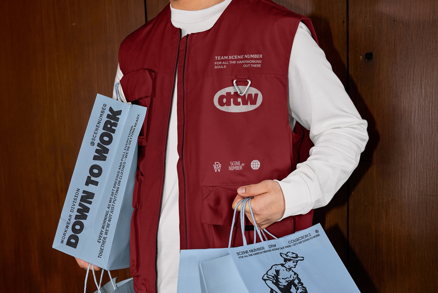 Burgundy puffer vest, white shirt, holding light blue paper bag with model showing collection lookbook