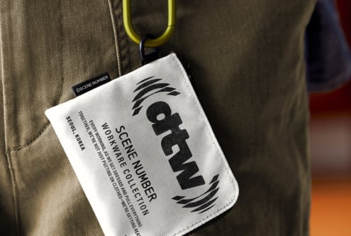 White fabric tag with yellow carabiner clip on tweed fabric background