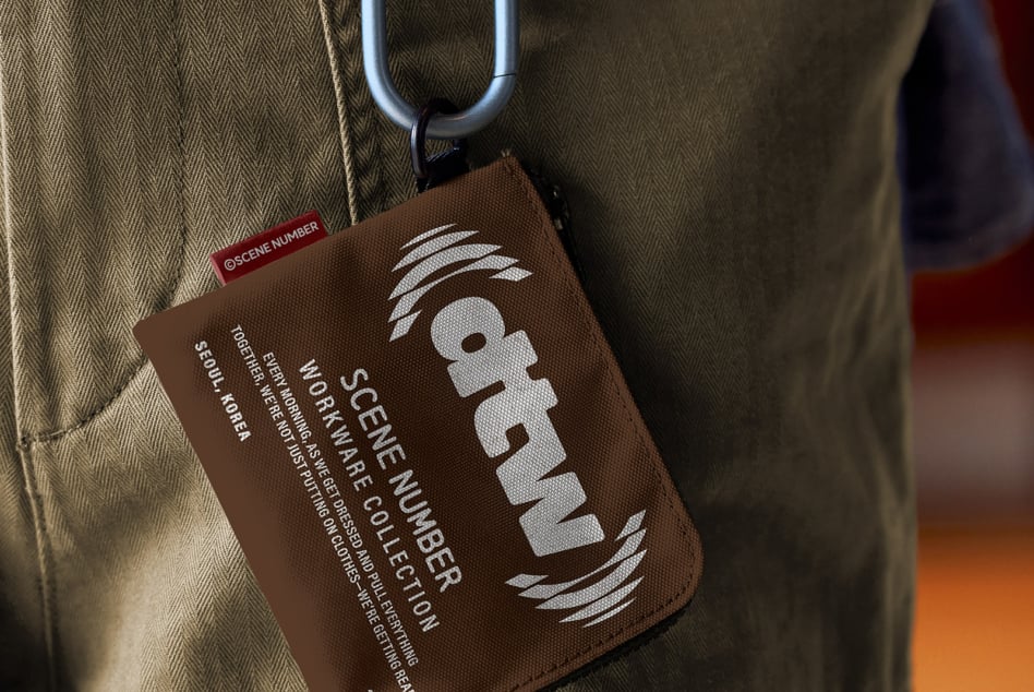 Brown fabric luggage tag with large white logo dangling from pants