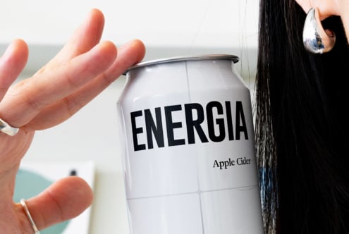 Hand holding open Energia apple cider can with water dripping down side