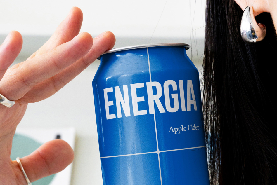 Blue Energia can held up against cloudy sky with person wearing silver drop earring