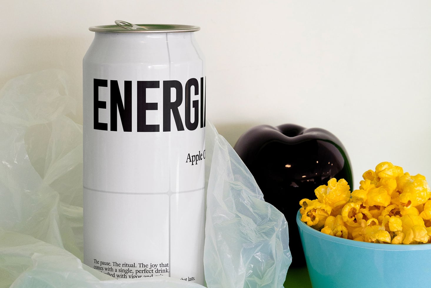 White ENERGIA can beside popcorn in turquoise bowl on cream backdrop