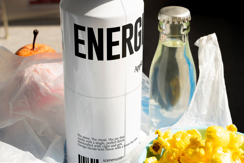 Energy drink can surrounded by yellow flowers, bottle, orange fruit with styled props