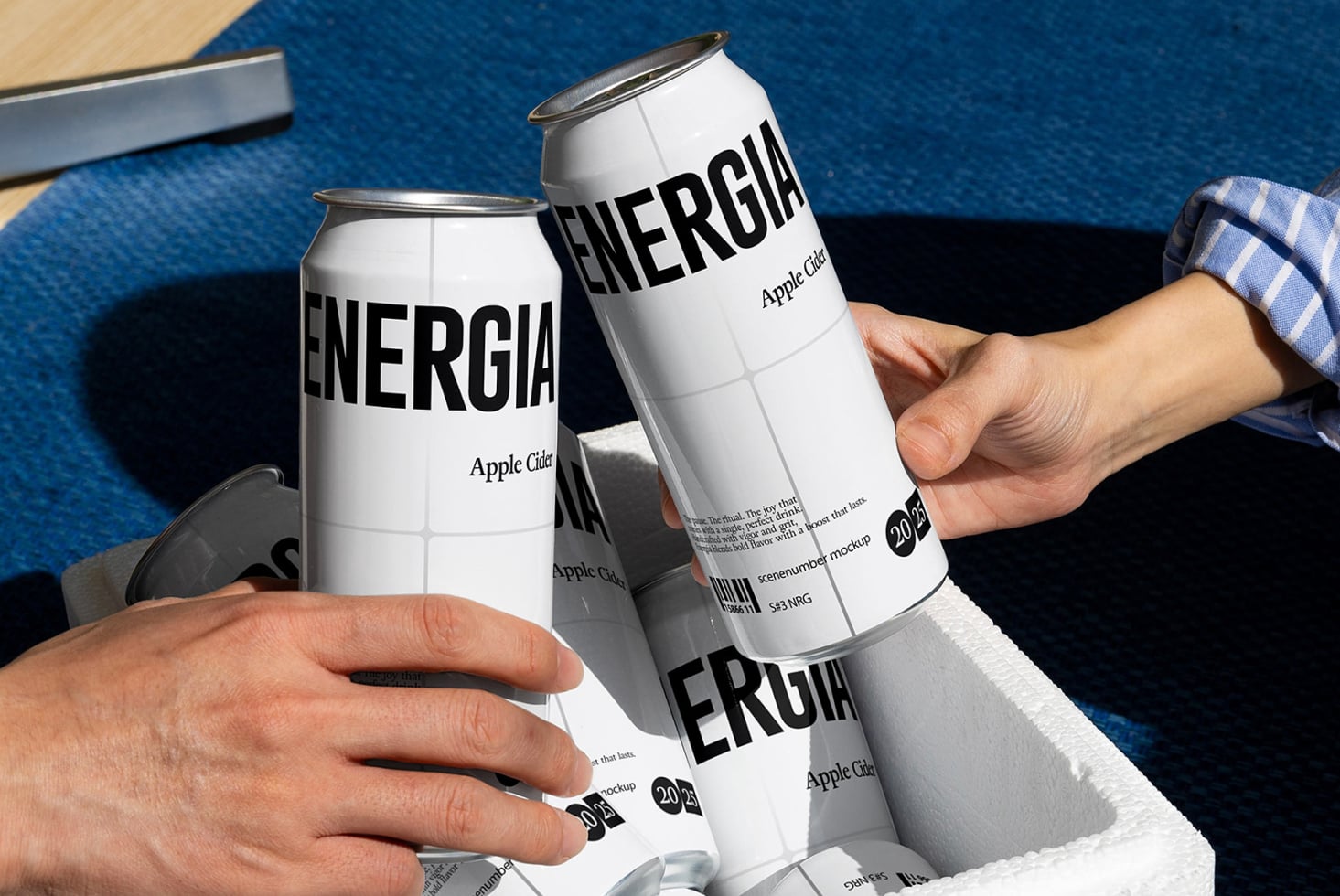 Two people toasting white ENERGIA cans on blue textured surface