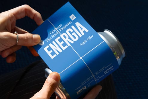 Hands holding blue can with ENERGIA label in minimalist grid design