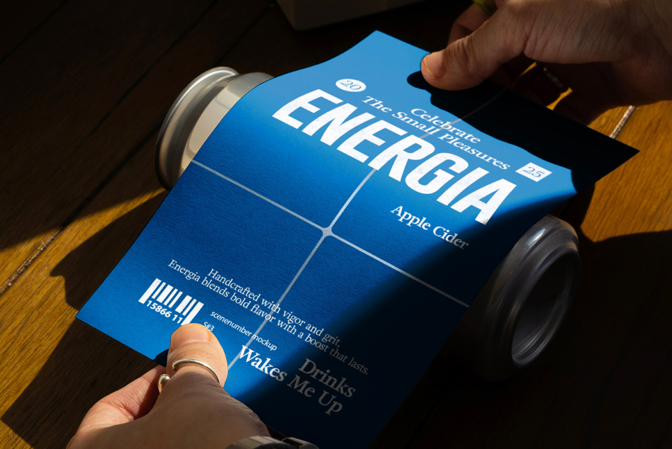 Blue energy can label mockup being held over wooden table surface