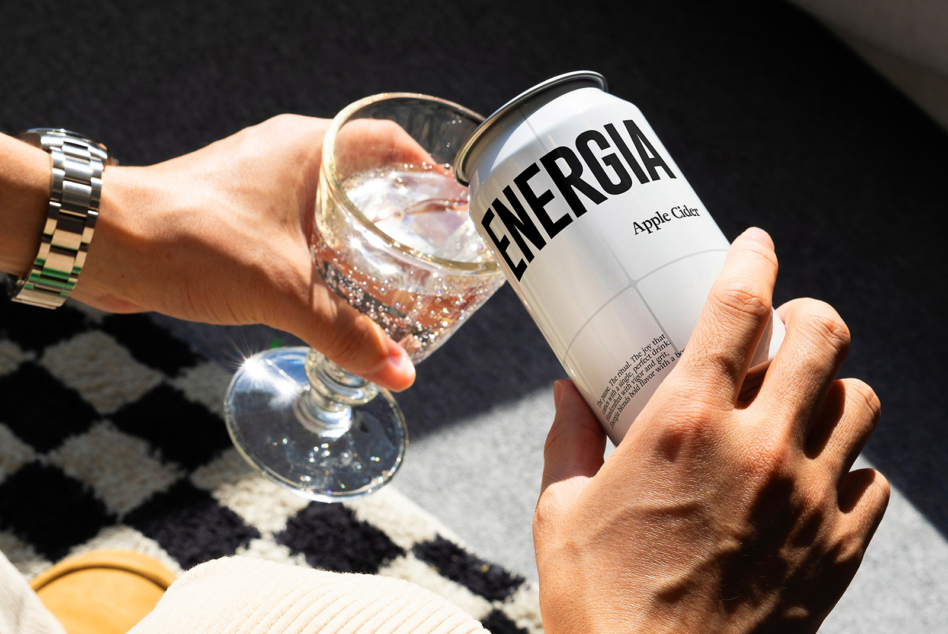 White soda can with sparkling drink in glass on checkered fabric in bright sunlight