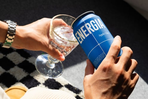 Blue soda can with sparkling beverage in glass on black diamond patterned fabric