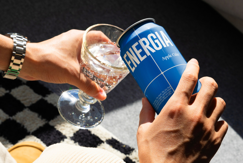Blue soda can with sparkling beverage in glass on black diamond patterned fabric