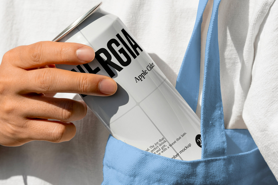 Hand holding white Energia can with blue fabric in background