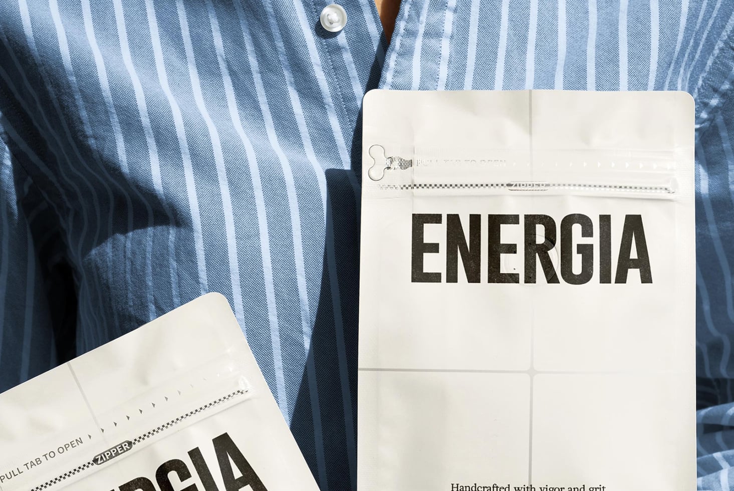 Striped shirt with white packet showing ENERGIA, open zipper detail, grid pattern visible
