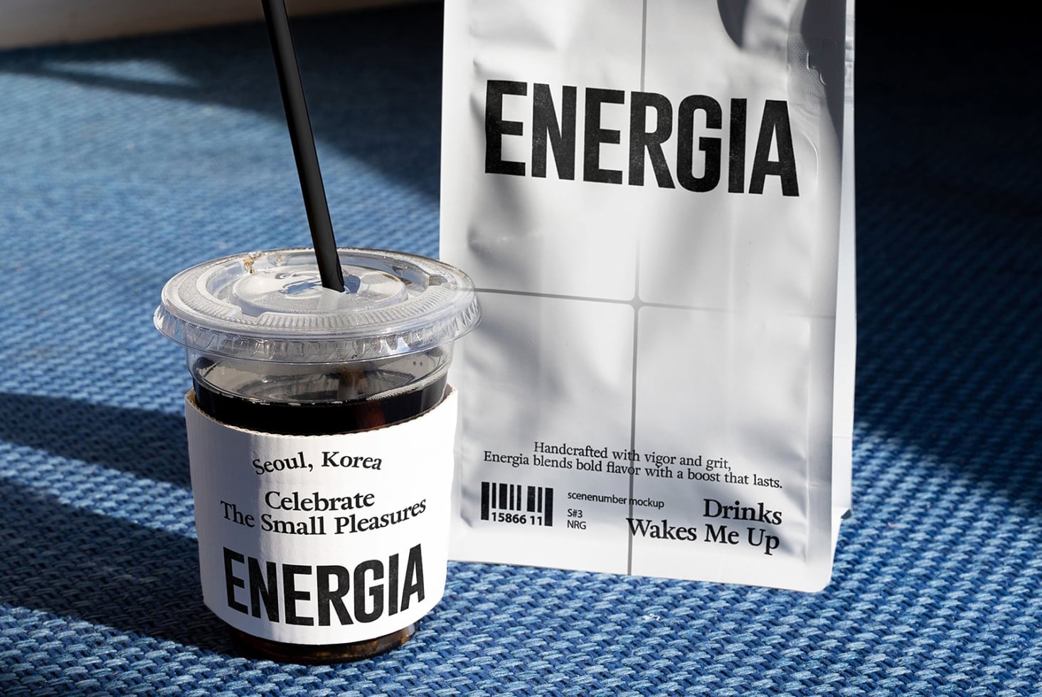 Cold brew cup with straw next to Energia pouch on blue textured surface