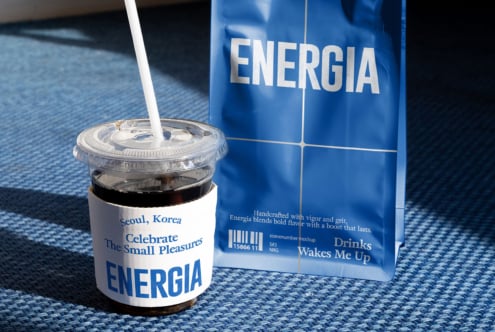 Clear cup with white straw, blue carton nearby on blue fabric in daylight