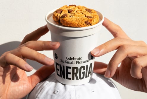 White cup with chocolate cookies held in hands, Energia label on packaging
