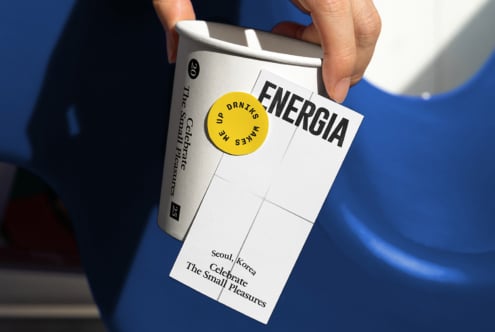 White can with yellow circular sticker, Energia card detail shot against blue
