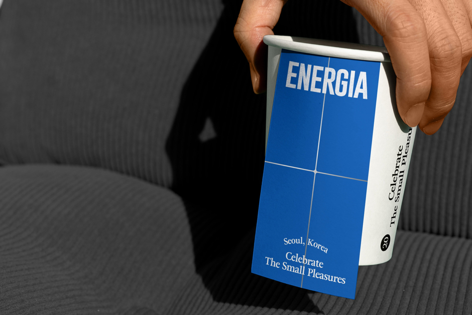 Hand holding blue box with ENERGIA text, white side panel showing Seoul Korea tagline