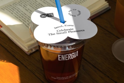 Cup with cloud-shaped white lid sits on book with blue straw poking through