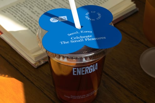Blue flower-shaped lid on Energia cup with white straw in overhead view