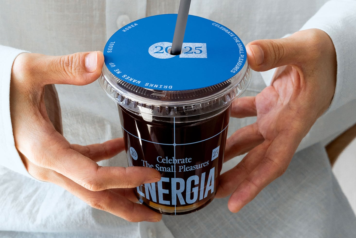 Beverage cup with bright blue lid, dark straw, date badge 20-25