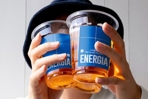 Two clear cups with blue Energia labels held up to sunlight