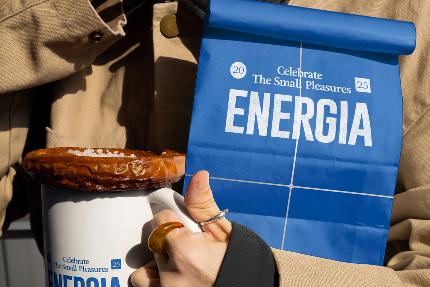 Blue paper bag mockup with Energia branding next to white mug with pastry