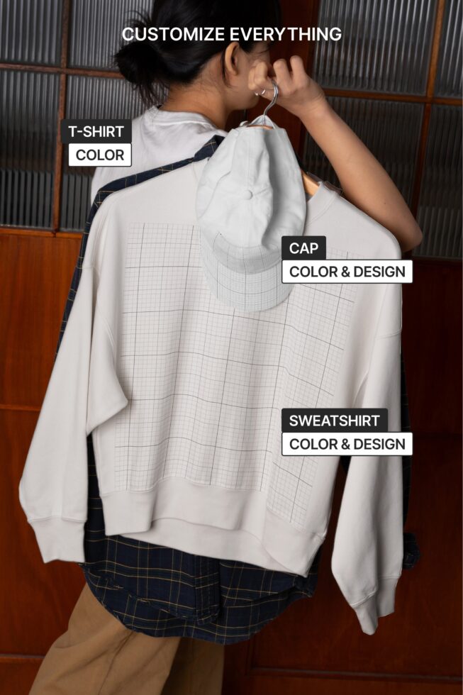 Person holding white sweatshirt showing customizable design areas for tee cap shirt