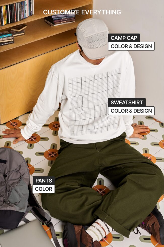 Person sitting wearing white camp cap, grid sweatshirt, olive pants in styled room