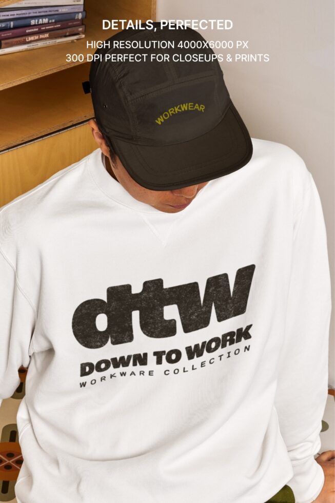 Close up of black cap with yellow workwear embroidery on white sweatshirt