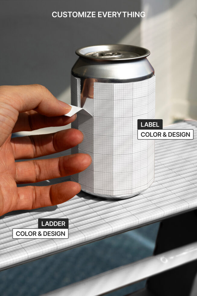 Aluminum can with blank gridded label held in hand over white surface