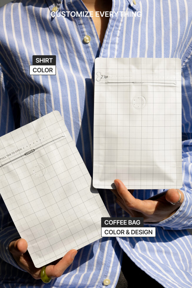 Grid-patterned mockup pages held by hands wearing blue striped shirt outdoors