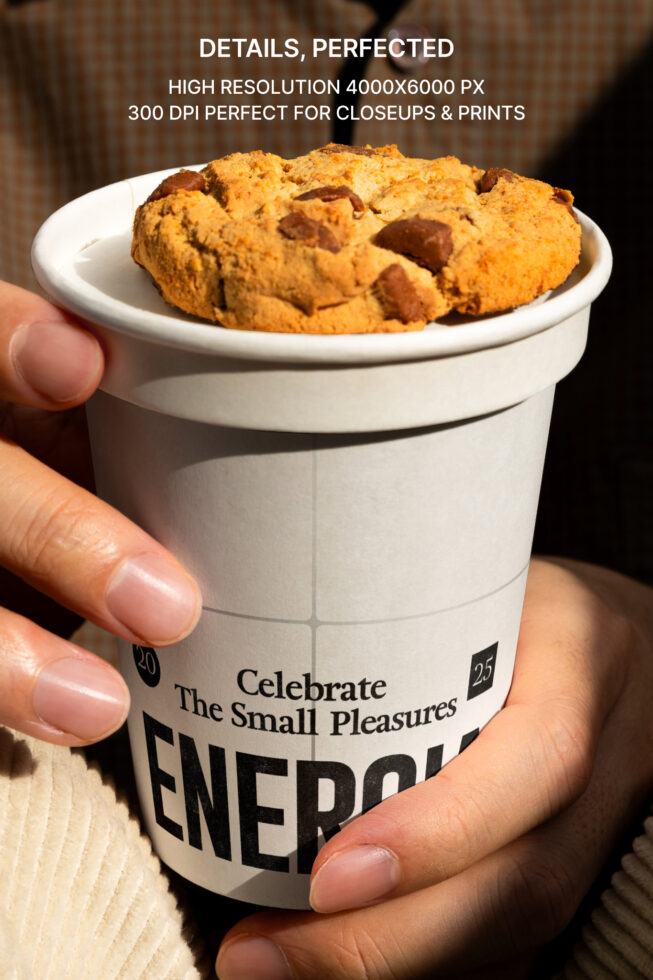 Hand holding white paper cup with chocolate chip cookies stacked inside