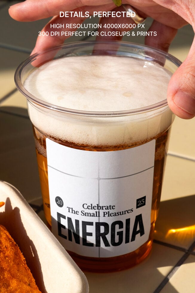 Close up of cola cup with Energia label, foam top, held in fingers