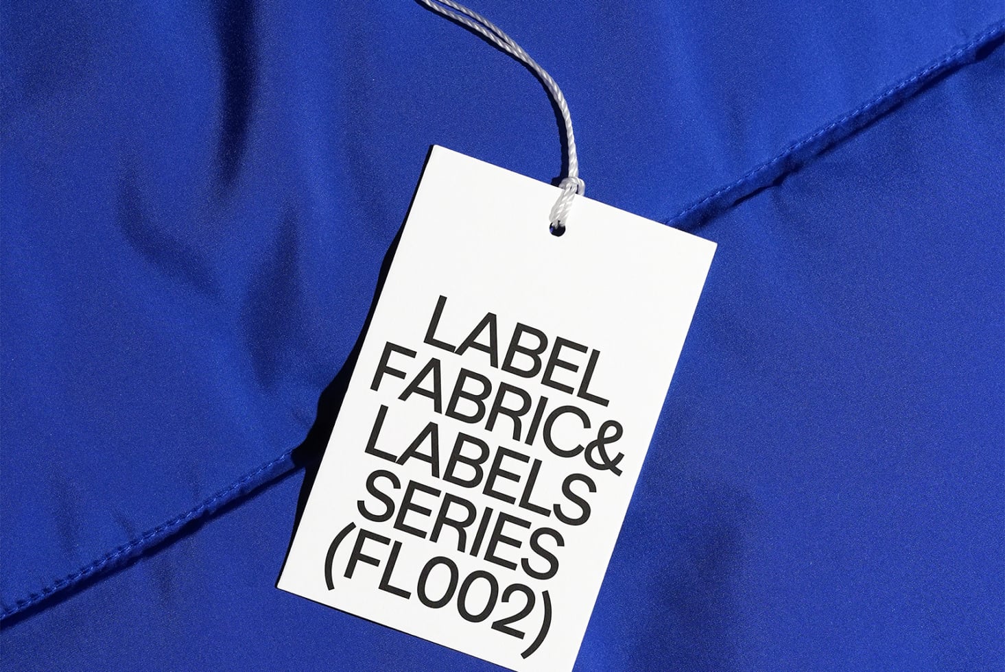 White hang tag with black text on bright cobalt blue fabric surface