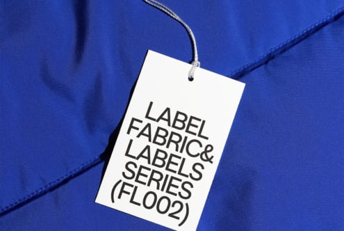 White hang tag with black text on bright cobalt blue fabric surface