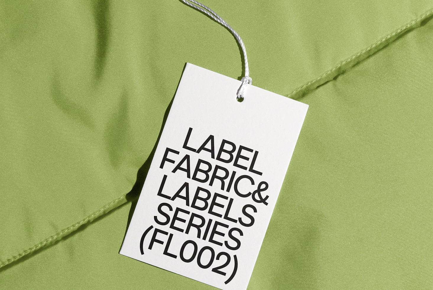 White hang tag with black text hanging on lime green nylon fabric