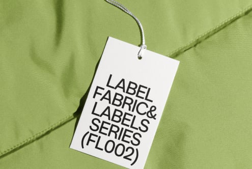 White hang tag with black text hanging on lime green nylon fabric