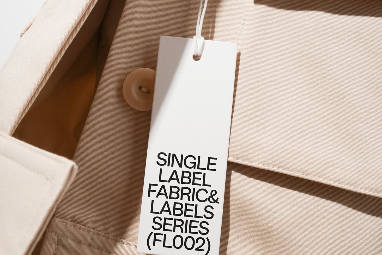 White hang tag with black text on beige cotton fabric material