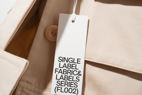 White hang tag with black text on beige cotton fabric material