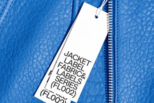 Blue textured leather jacket with a white tag label attached, featuring bold lettering. Ideal for designing apparel mockups, fashion templates, branding.